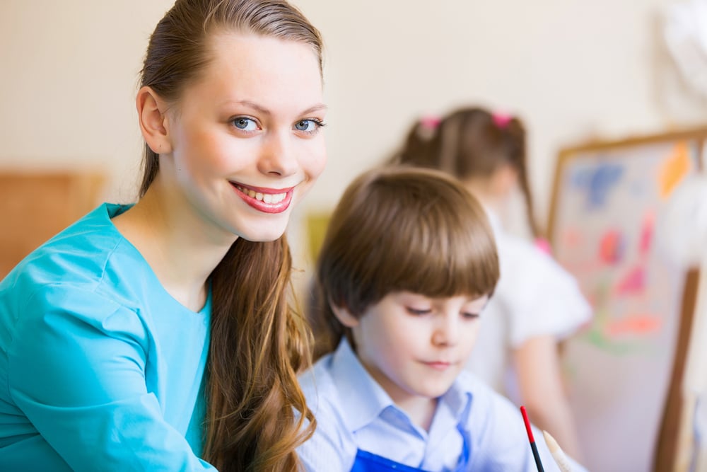 Young teacher and children painting and playing